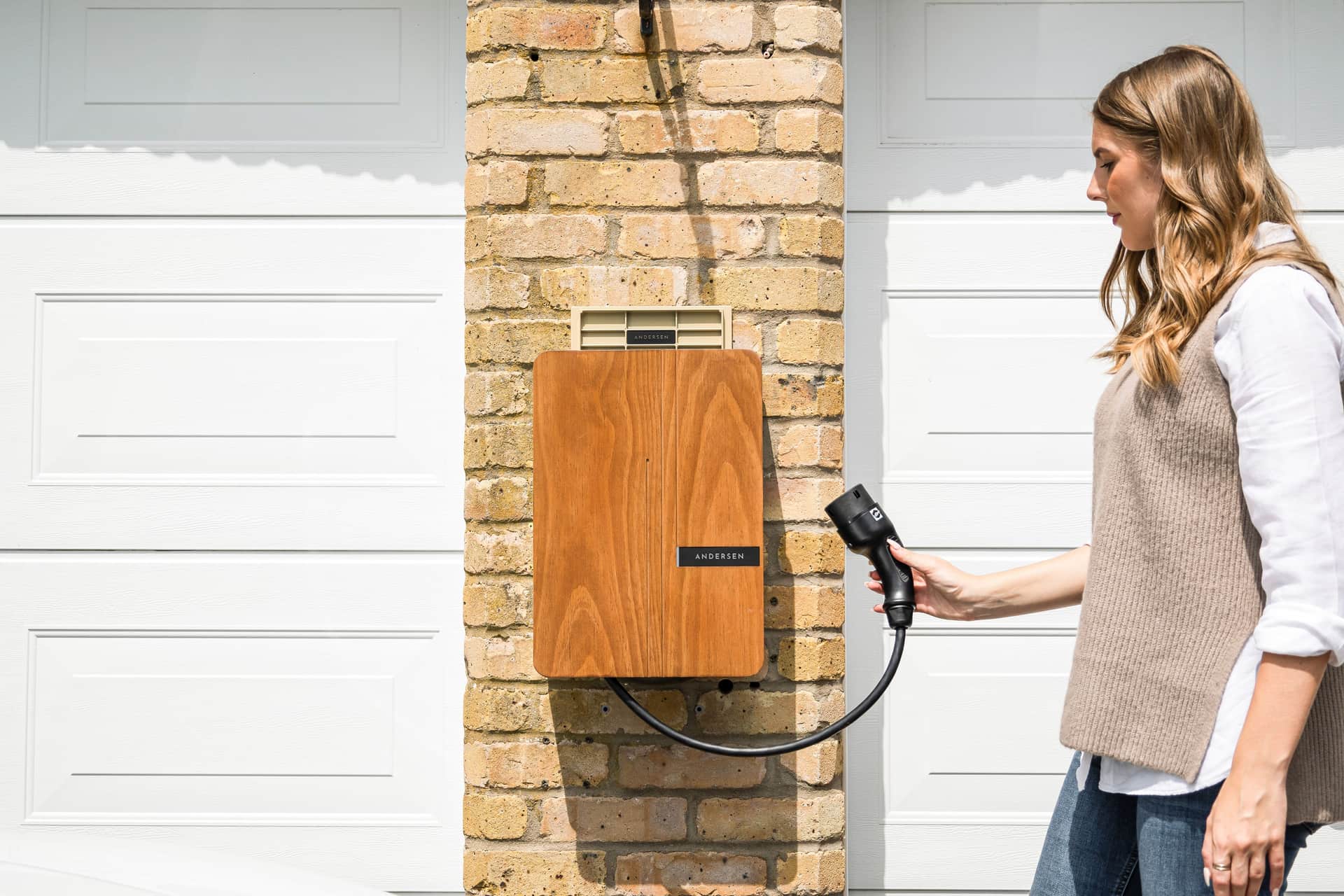 A Level 2 EV charger mounted beside a car in a residential garage