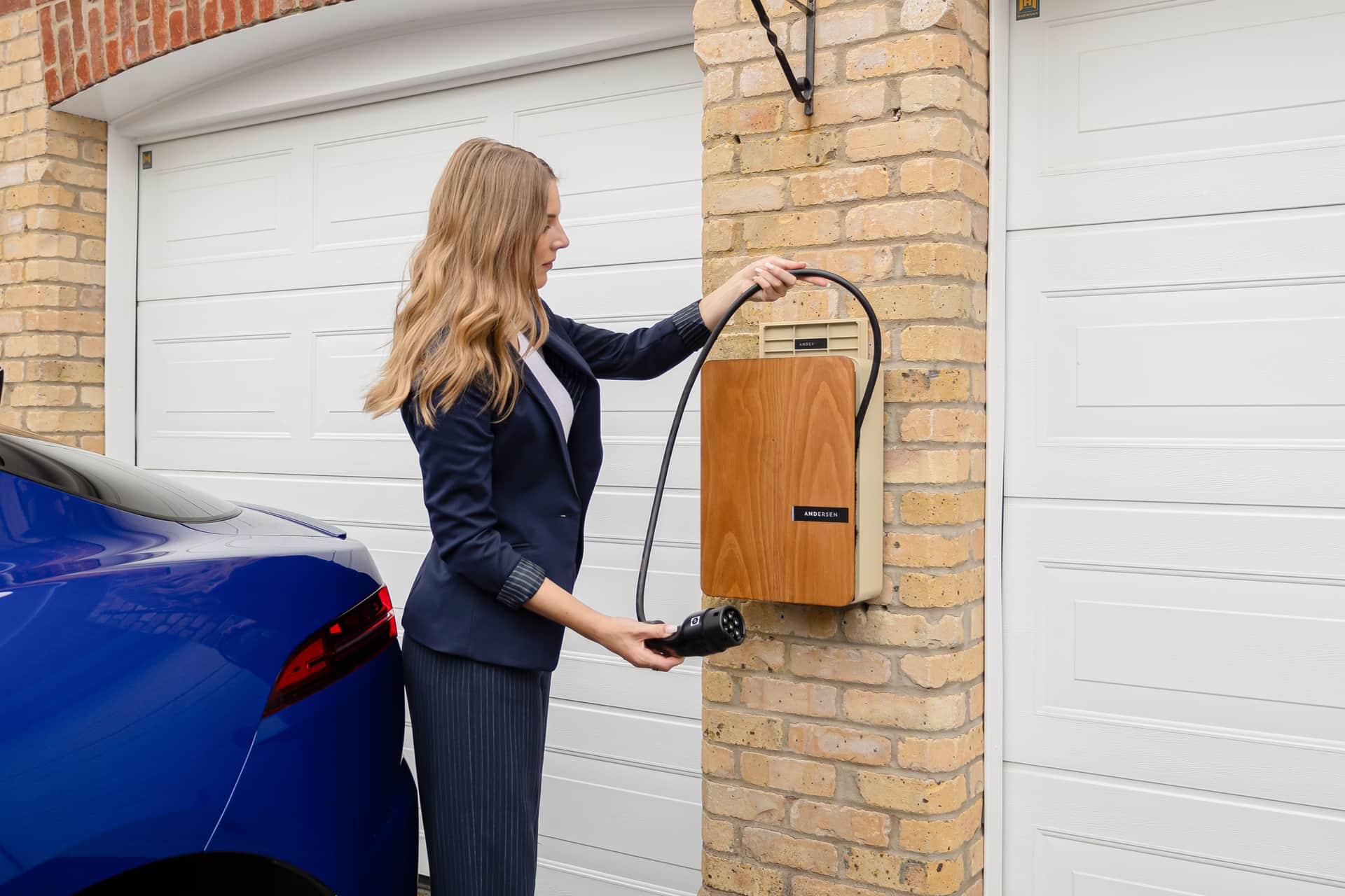 A wall-mounted Level 2 EV charger installed on the exterior wall of a house