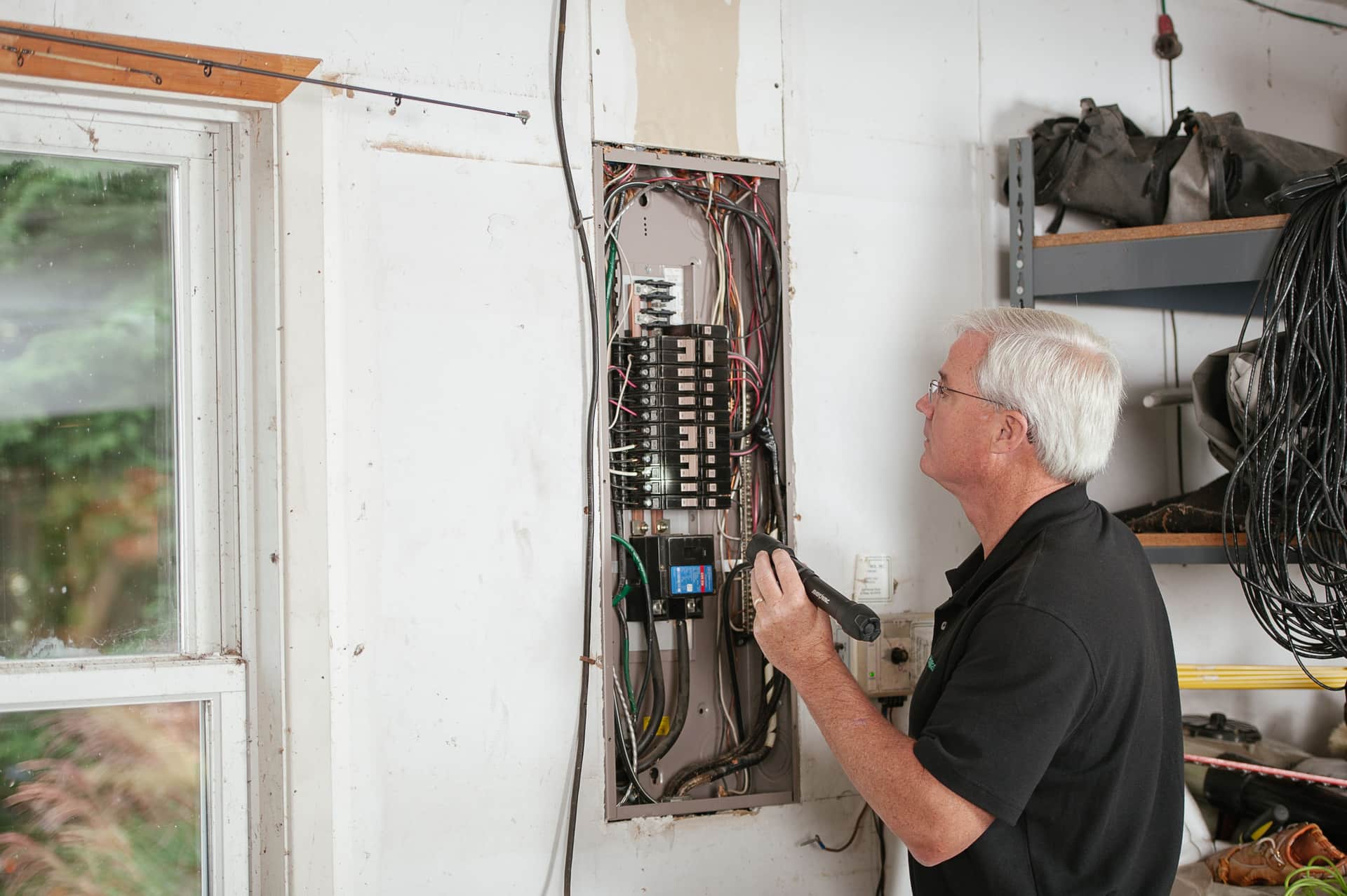 An electrician inspecting a residential electrical panel and breaker box