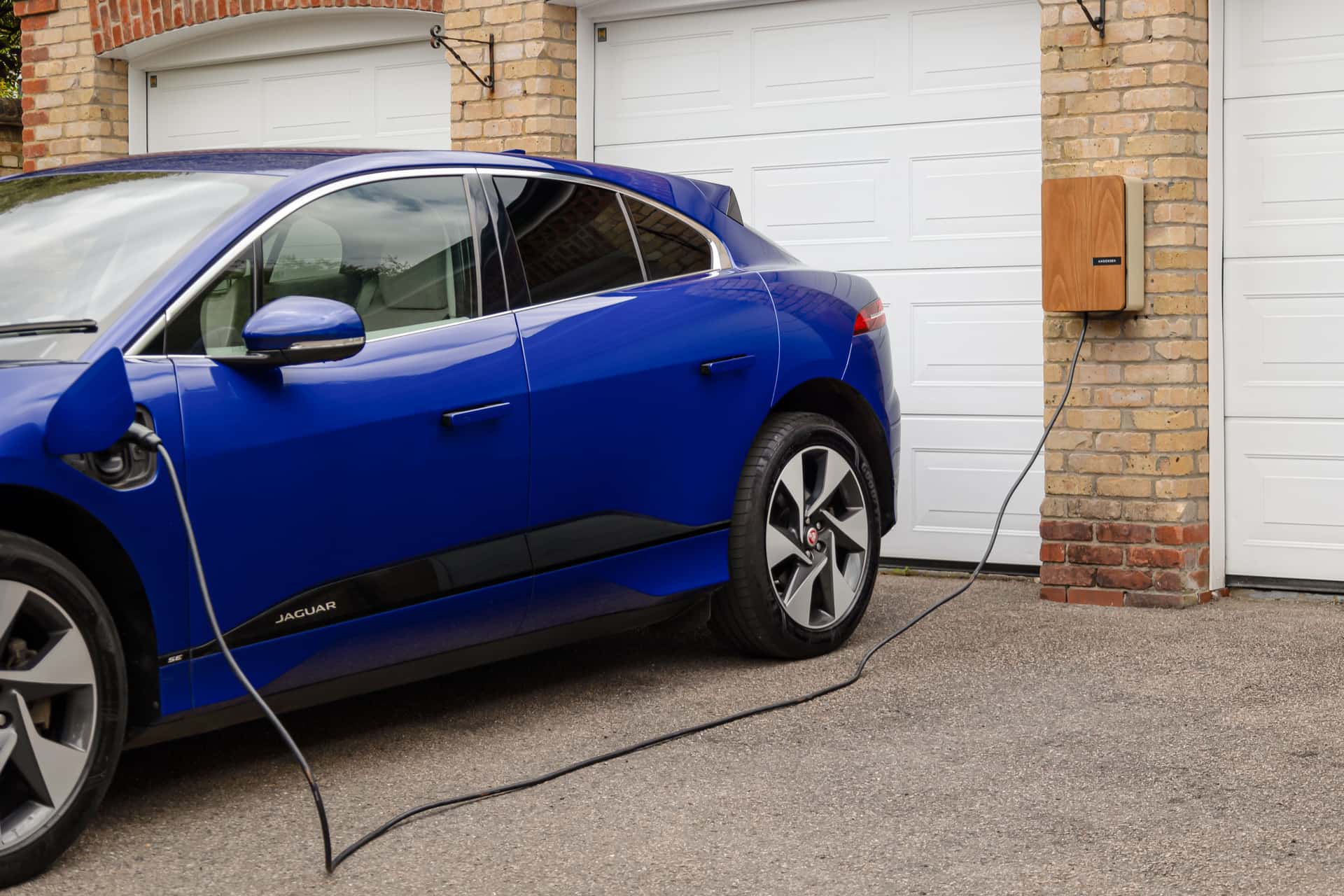 An EV charger mounted on an exterior wall beside a residential driveway
