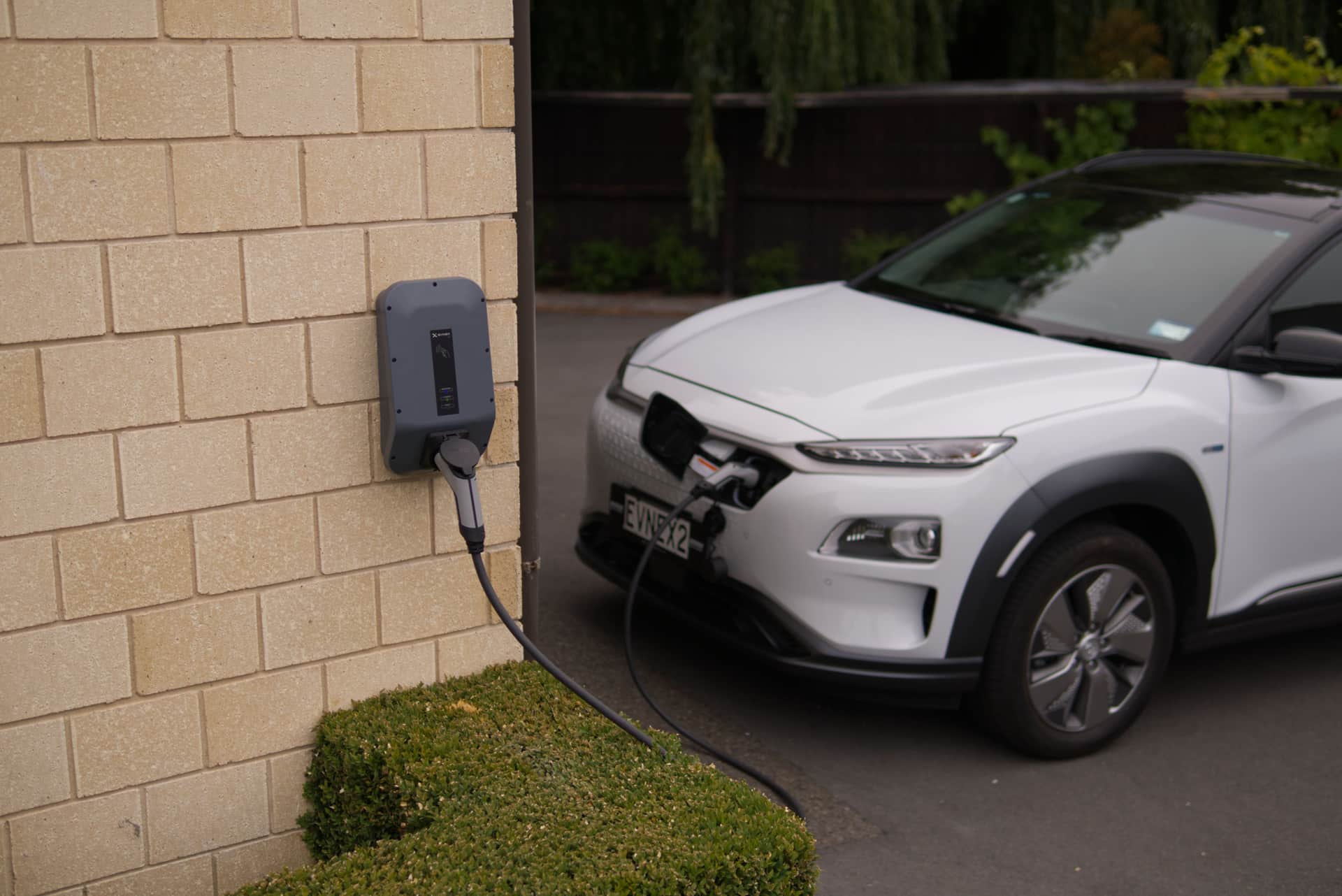 An electric car plugged in and charging on a residential driveway